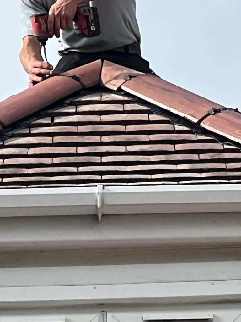 This is a photo of one of the operatives of Hillfield Roofing Repairs installing new ridge tiles